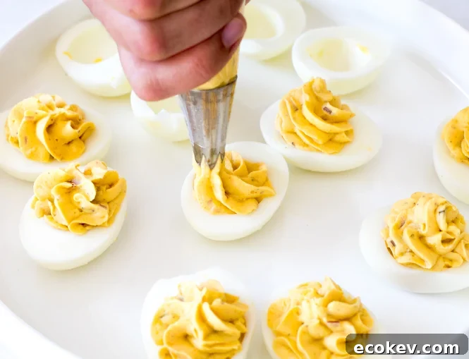 piping egg yolk mixture into eggs