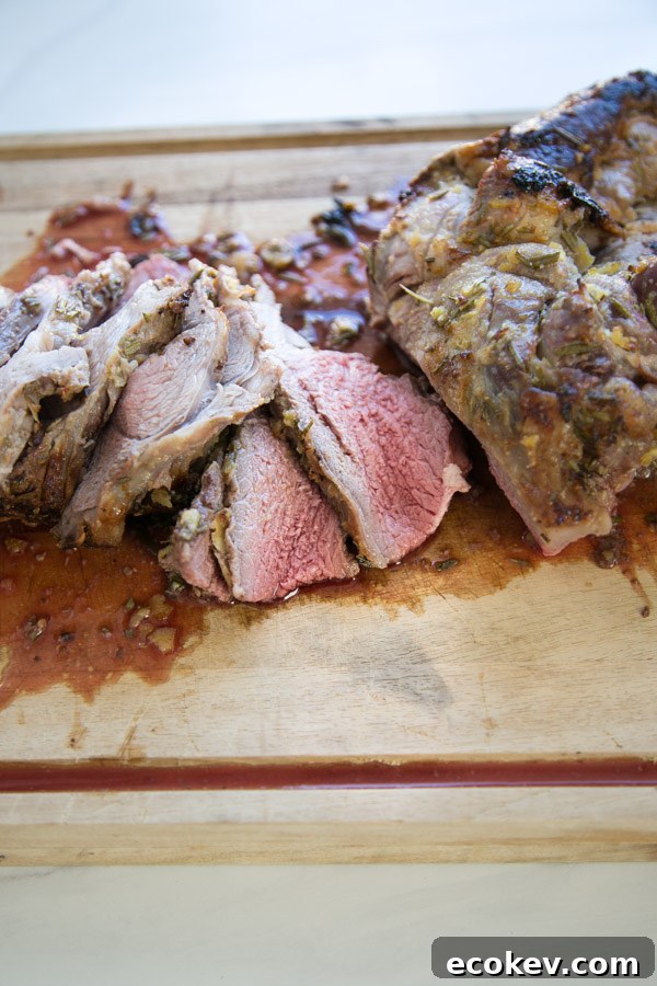 sliced medium rare boneless leg of lamb on a cutting board