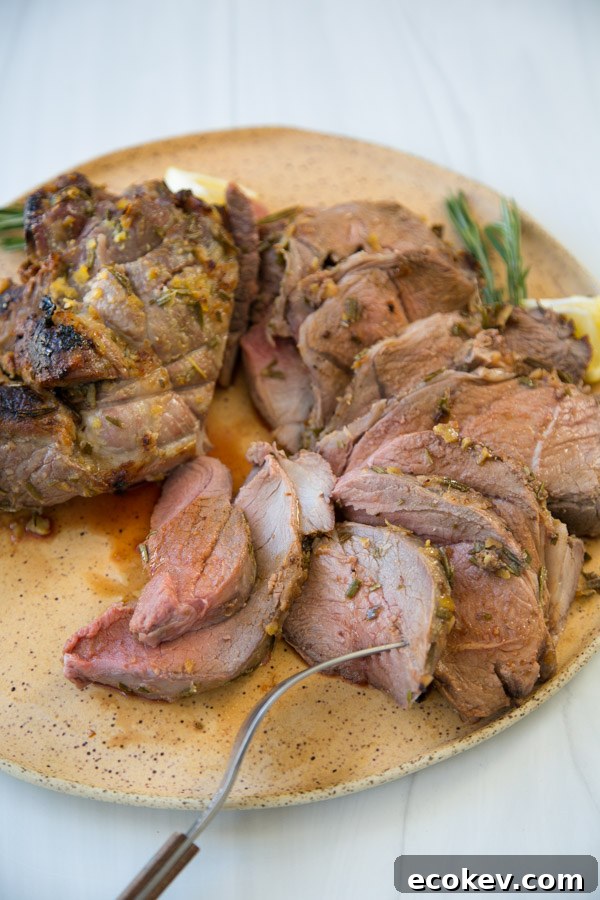 thinly sliced slow roasted boneless leg of lamb on a platter with fork