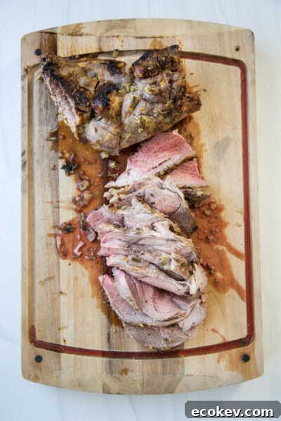 sliced medium rare boneless leg of lamb on a cutting board