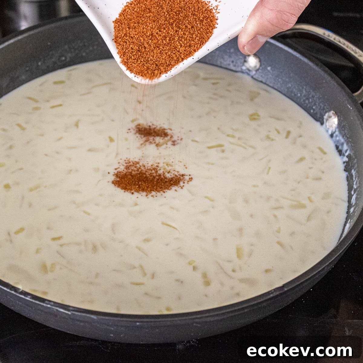 cajun seasoning being poured into a roux.