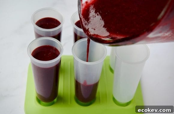Pouring blackberry mojito mixture into popsicle molds