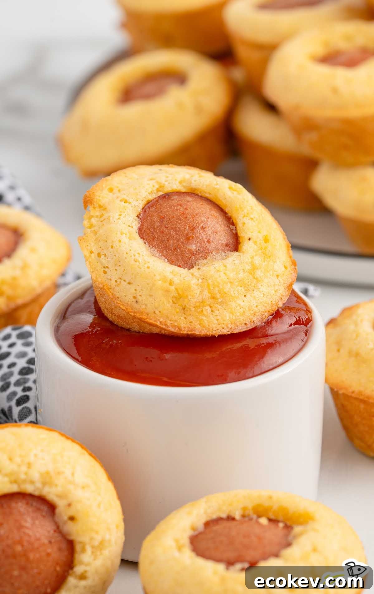 Close-up of stacked corn dog muffins next to a bowl of ketchup.
