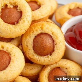 Close-up of corn dog muffins with ketchup, text overlay "Corn Dogs Muffins."