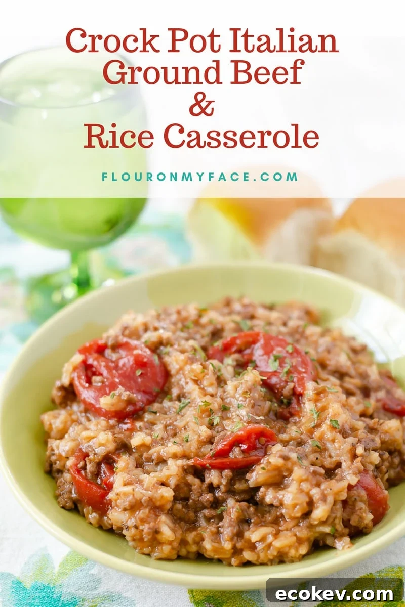 Crock Pot Italian Ground Beef and Rice Casserole served in a green bowl with a glass of water and fresh rolls.