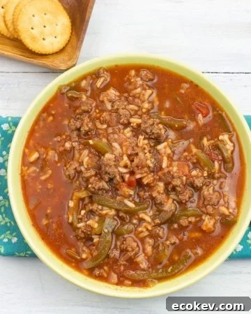Instant Pot Stuffed Pepper Soup served in a green glass bowl with crackers on the side.