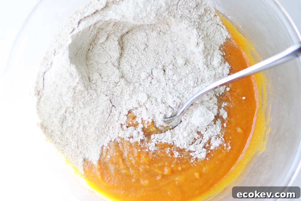 a mixture of dry and wet ingredients in a bowl of pumpkin muffin batter