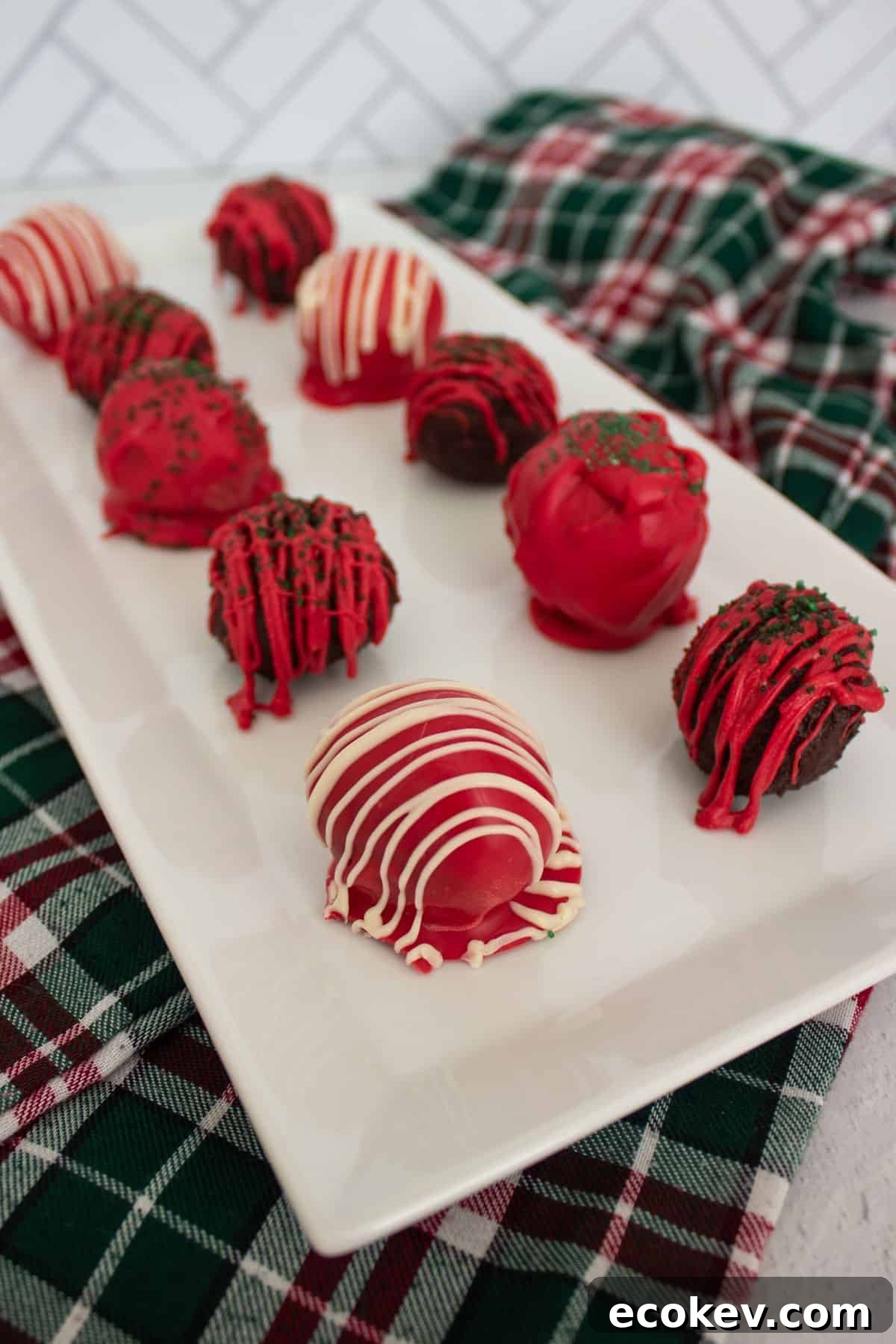 Red, white, and green decorated chocolate truffles on a white serving platter.