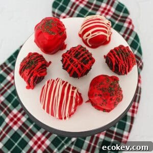 Red, white, and green decorated chocolate truffles on a white serving platter.