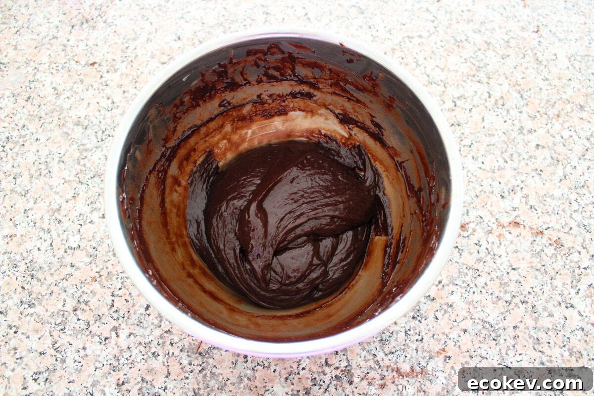 The chocolate and heavy cream fully combined in a bowl, smooth and glossy.