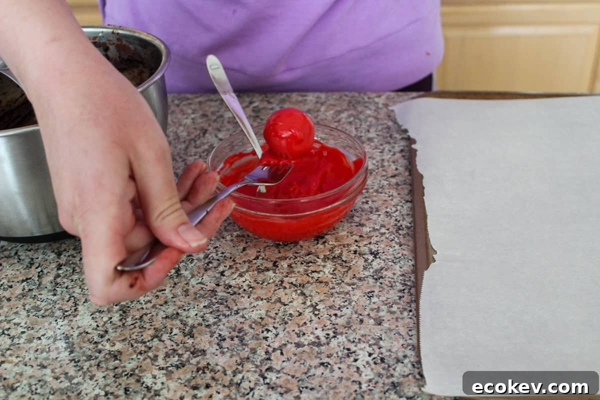 A truffle being lifted out of melted red wafer coating with a fork.