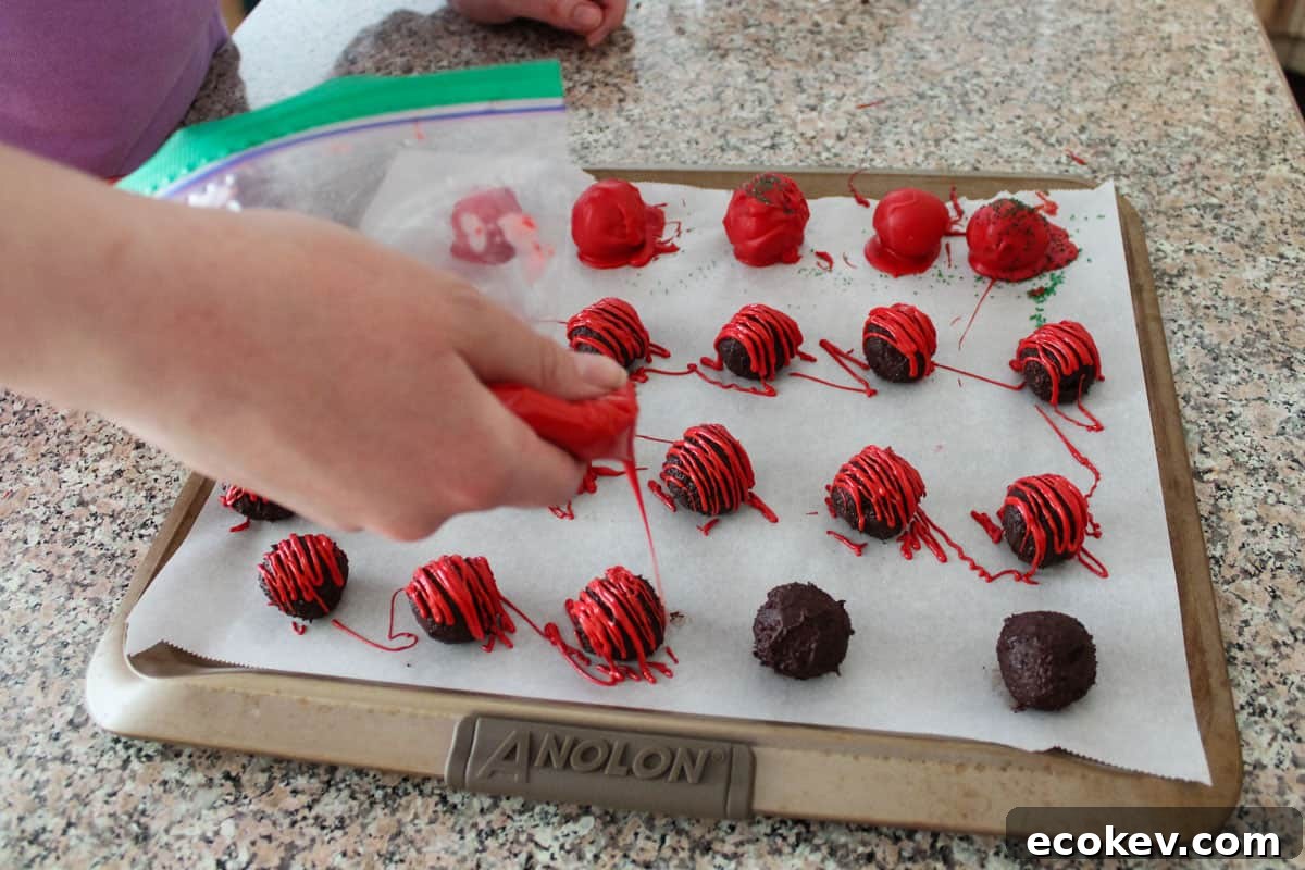 Someone drizzling melted wafers in a zip-top bag over some truffles, while others were dipped.