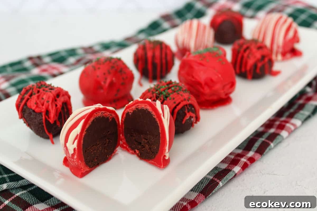 Red, white, and green decorated chocolate truffles on a white serving platter, the front one cut open.