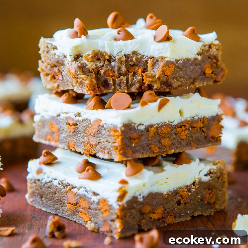 Stack of frosted brownies with chocolate chips.