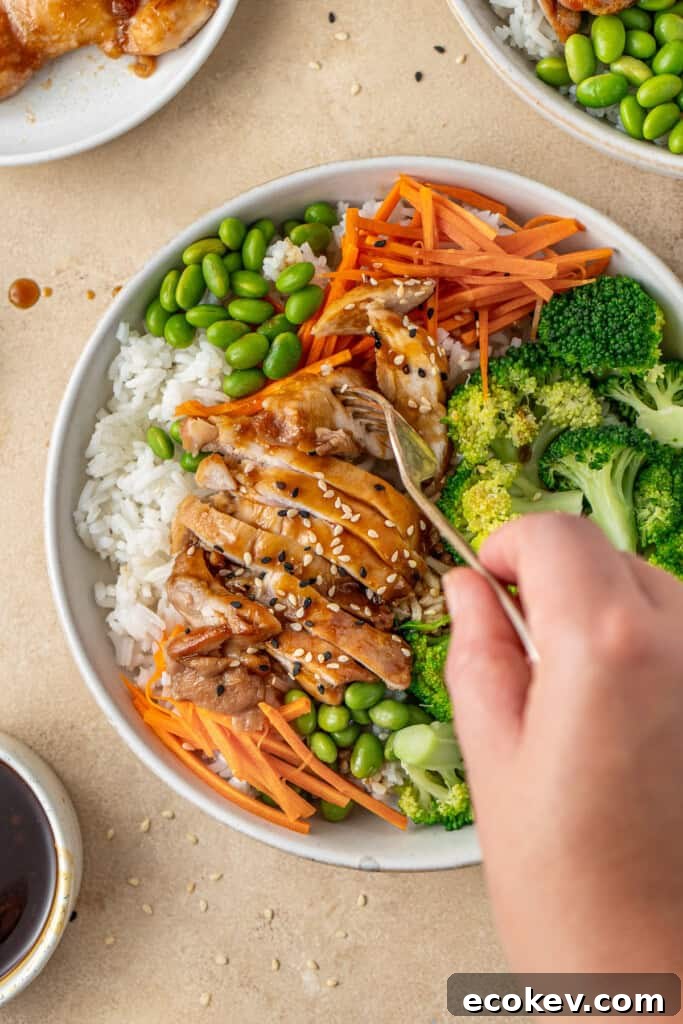 A hand with a fork taking a bite of chicken teriyaki rice bowls.