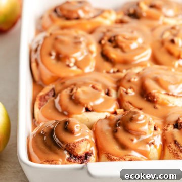 Close up view of caramel apple cinnamon rolls in a pan.