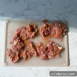 Chicken with seasoning on a cutting board.