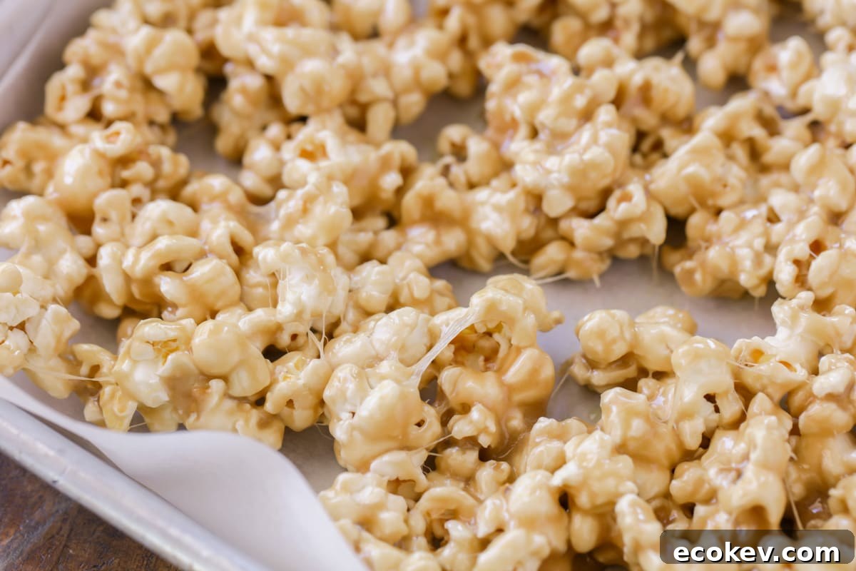 Gooey Caramel marshmallow popcorn on baking sheet lined with parchment paper.