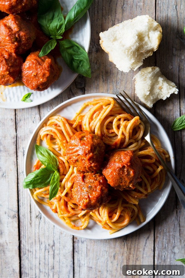 An overhead shot of mozzarella stuffed meatballs and spaghetti on a wooden surface with torn bread