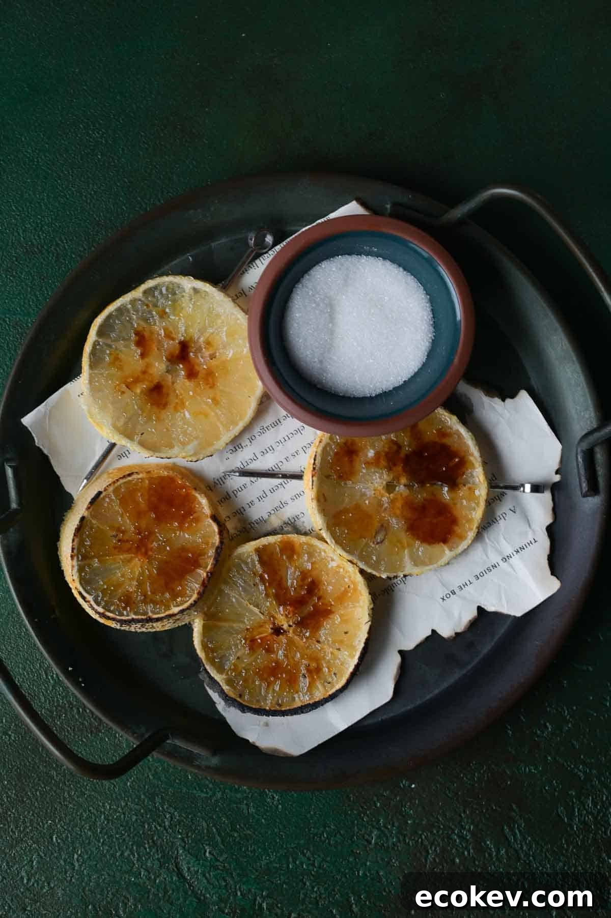 Lemon brûlée slices on a black tray with sugar.