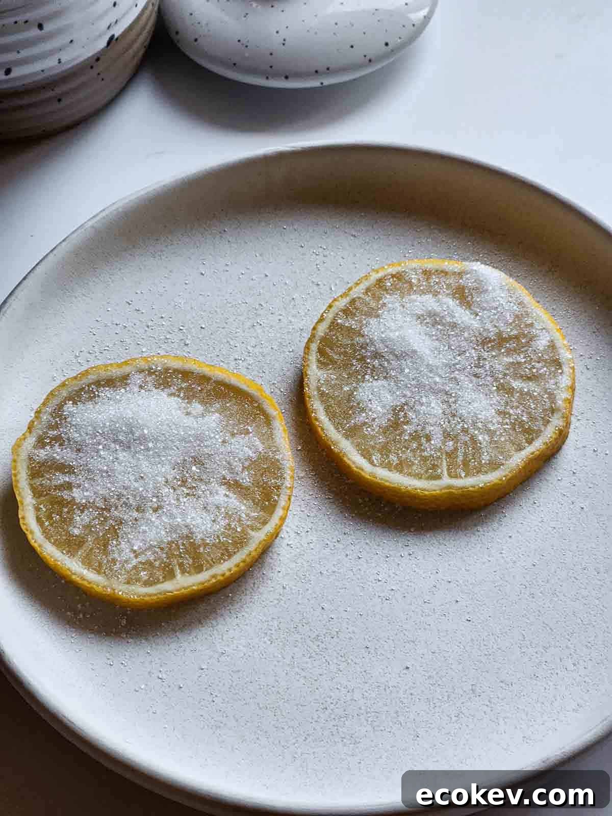 Two lemon slices with sugar on them on a white plate.