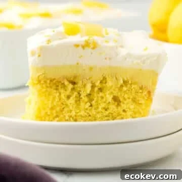 A piece of lemon poke cake garnished with lemon wedges.