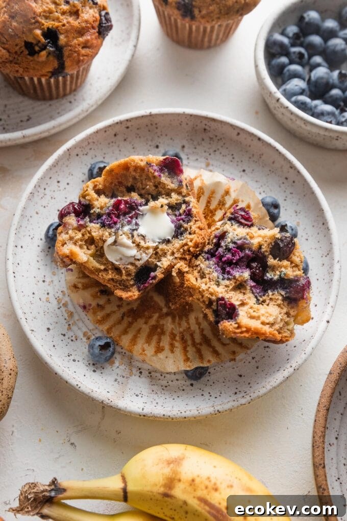 Blueberry banana muffin on a plate with butter smeared on the inside.