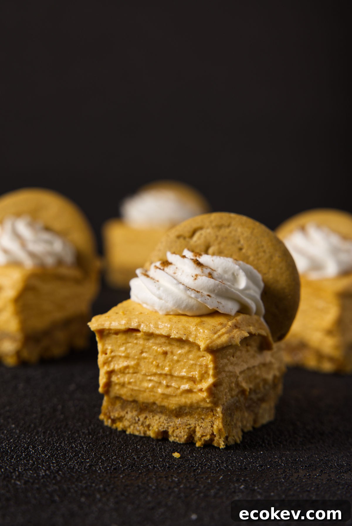 Very close up shot of no bake pumpkin cheesecake bars on a charcoal black surface.