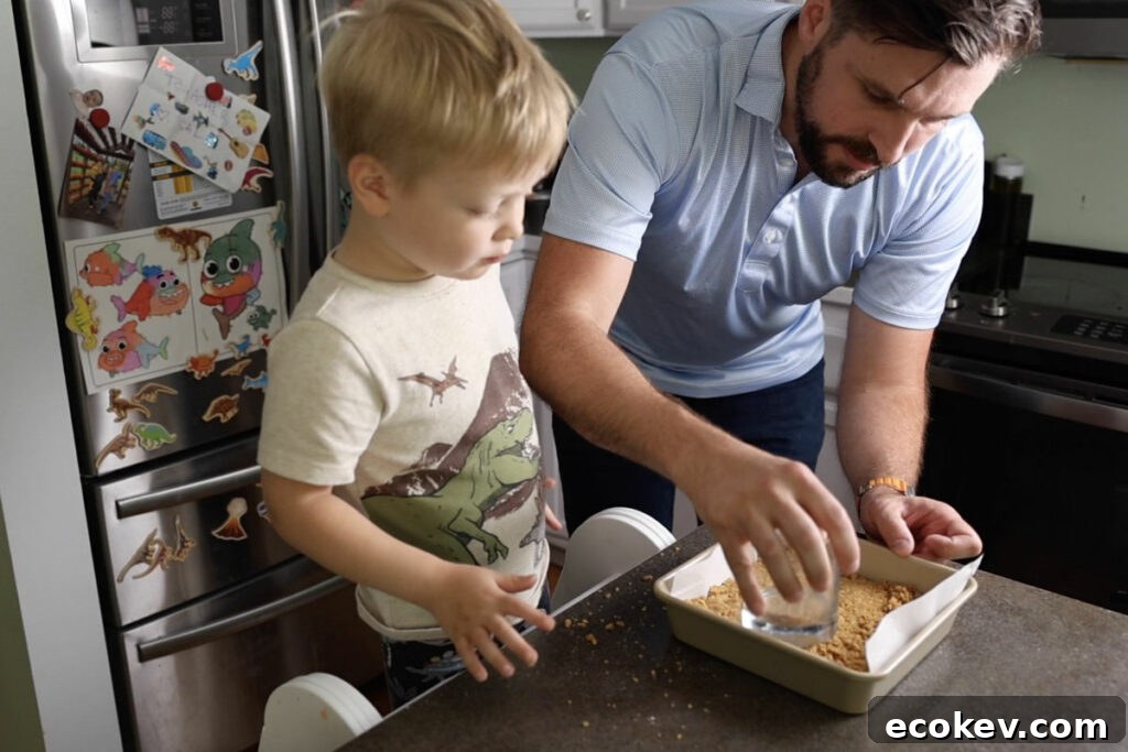 Using a glass to press cookie crumb crust into a square pan.
