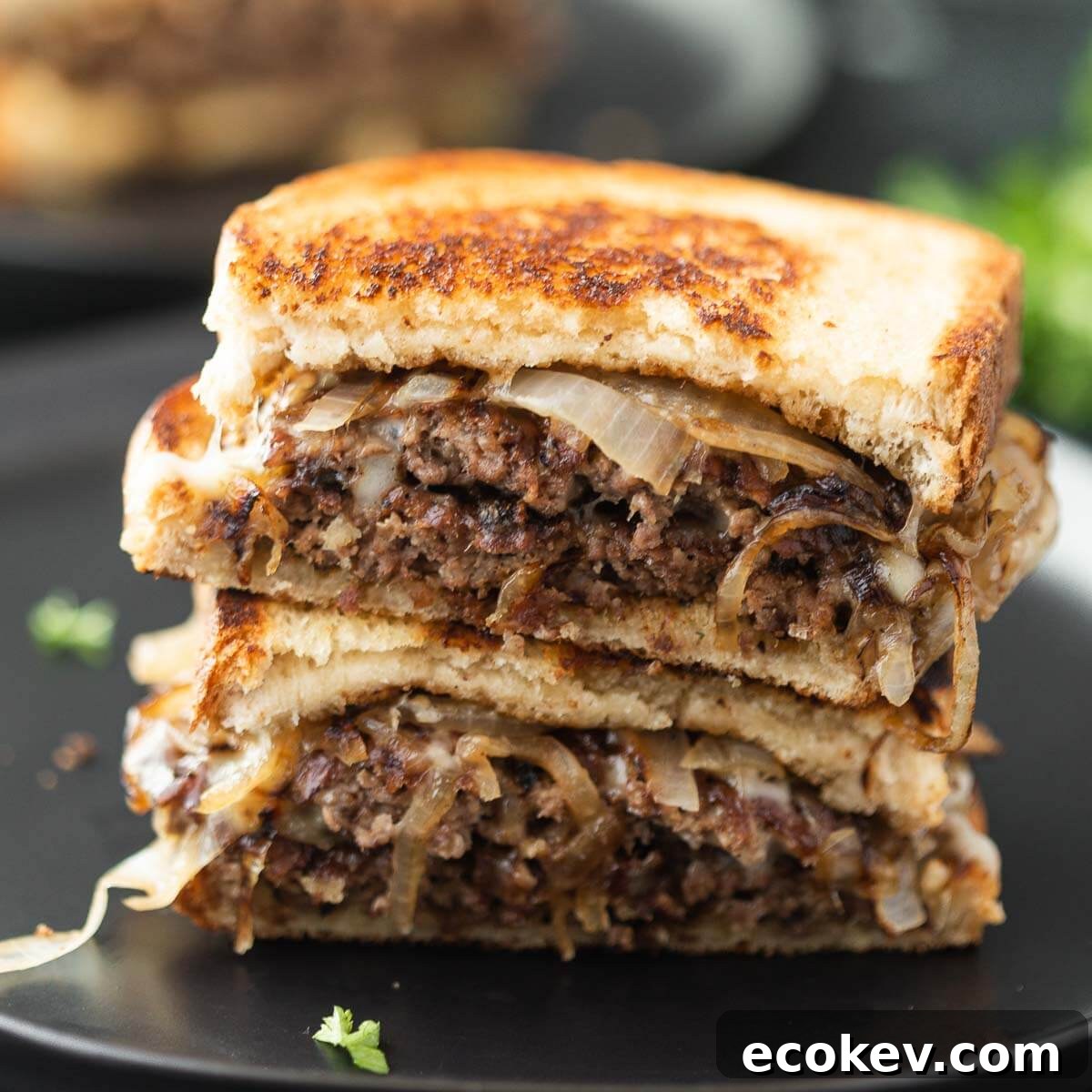 Patty Melt cut in half stacked on a black plate