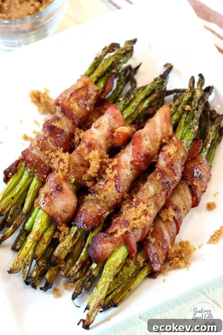 Bundles of bacon wrapped aparagus arranged on a square white plate.