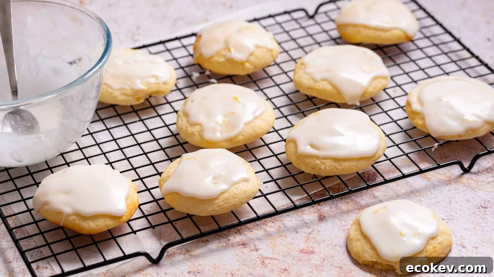Lemon ricotta cookies on rack with icing bowl.