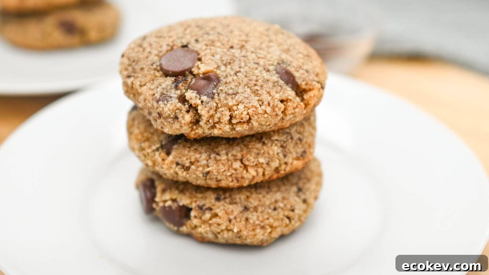 Three stacked chocolate chip cookies on a white plate.