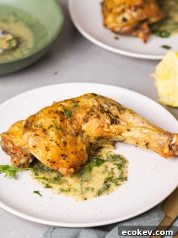 A serving of golden brown roasted chicken leg quarters with an herb sauce.