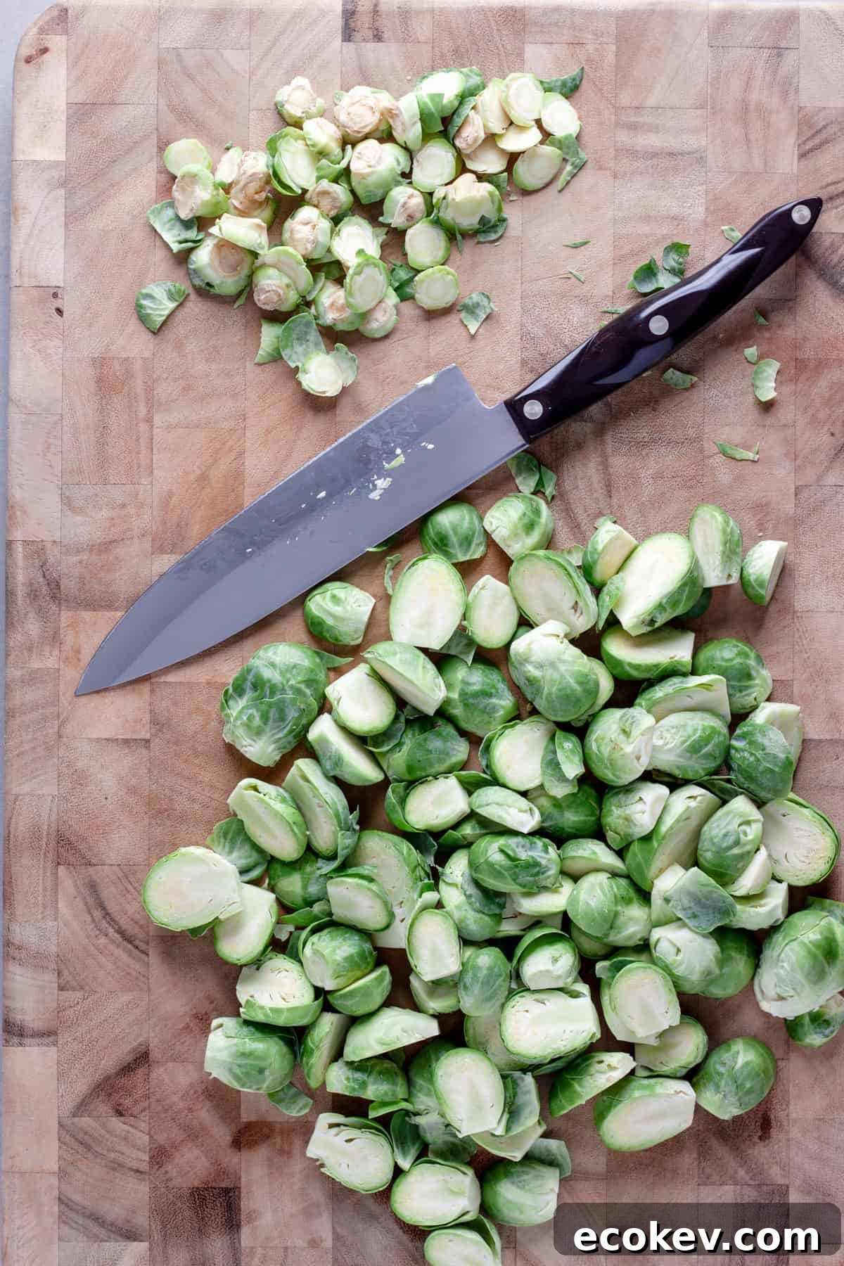 Brussels sprouts getting cut in half on a cutting board.