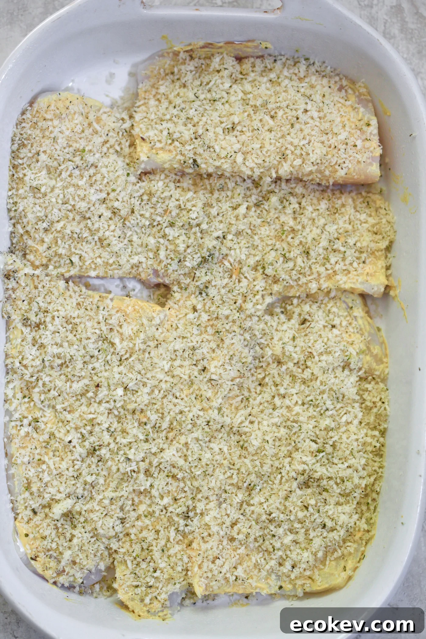 raw cod in baking dish with breadcrumbs on top