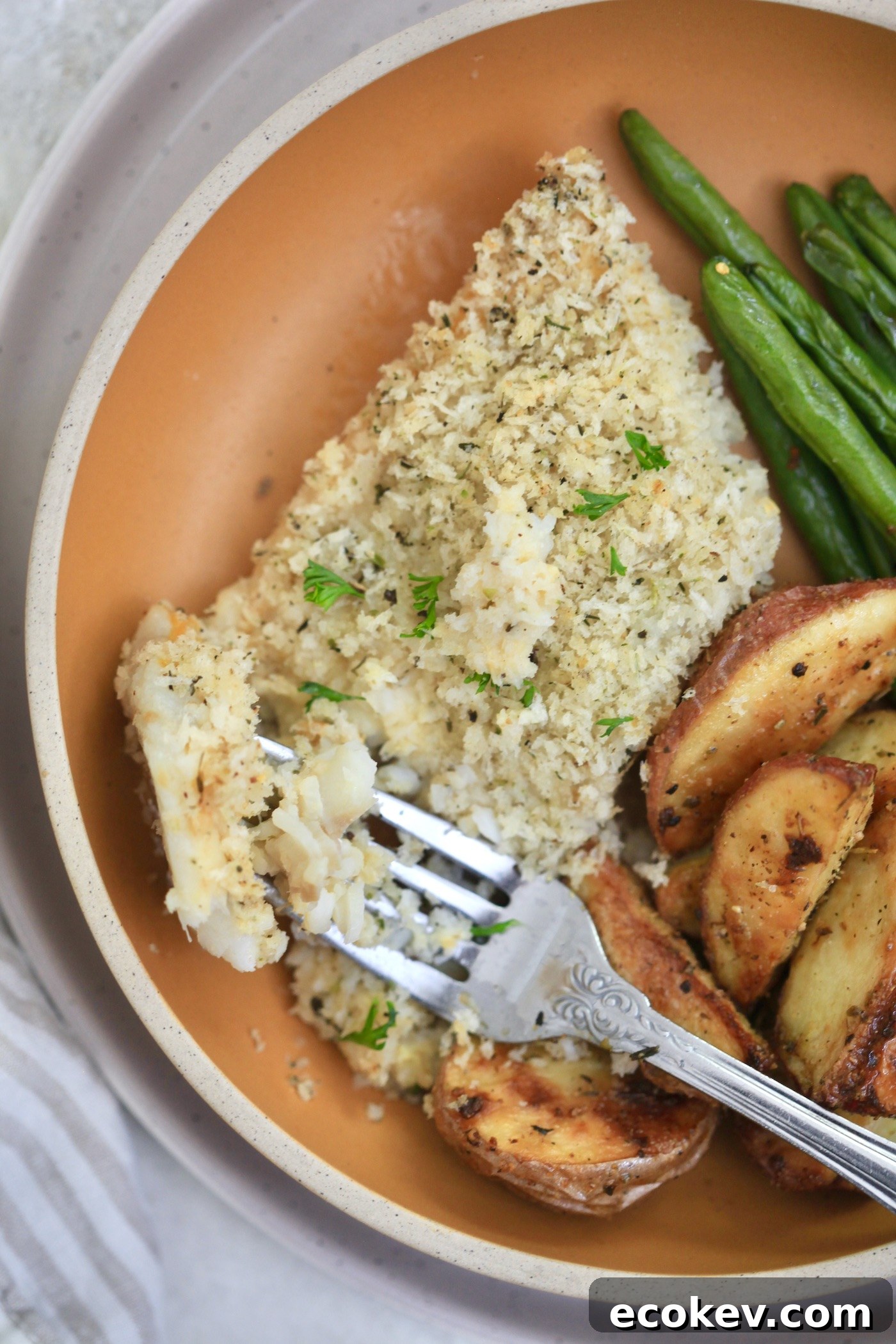 fork cutting into cod on plate