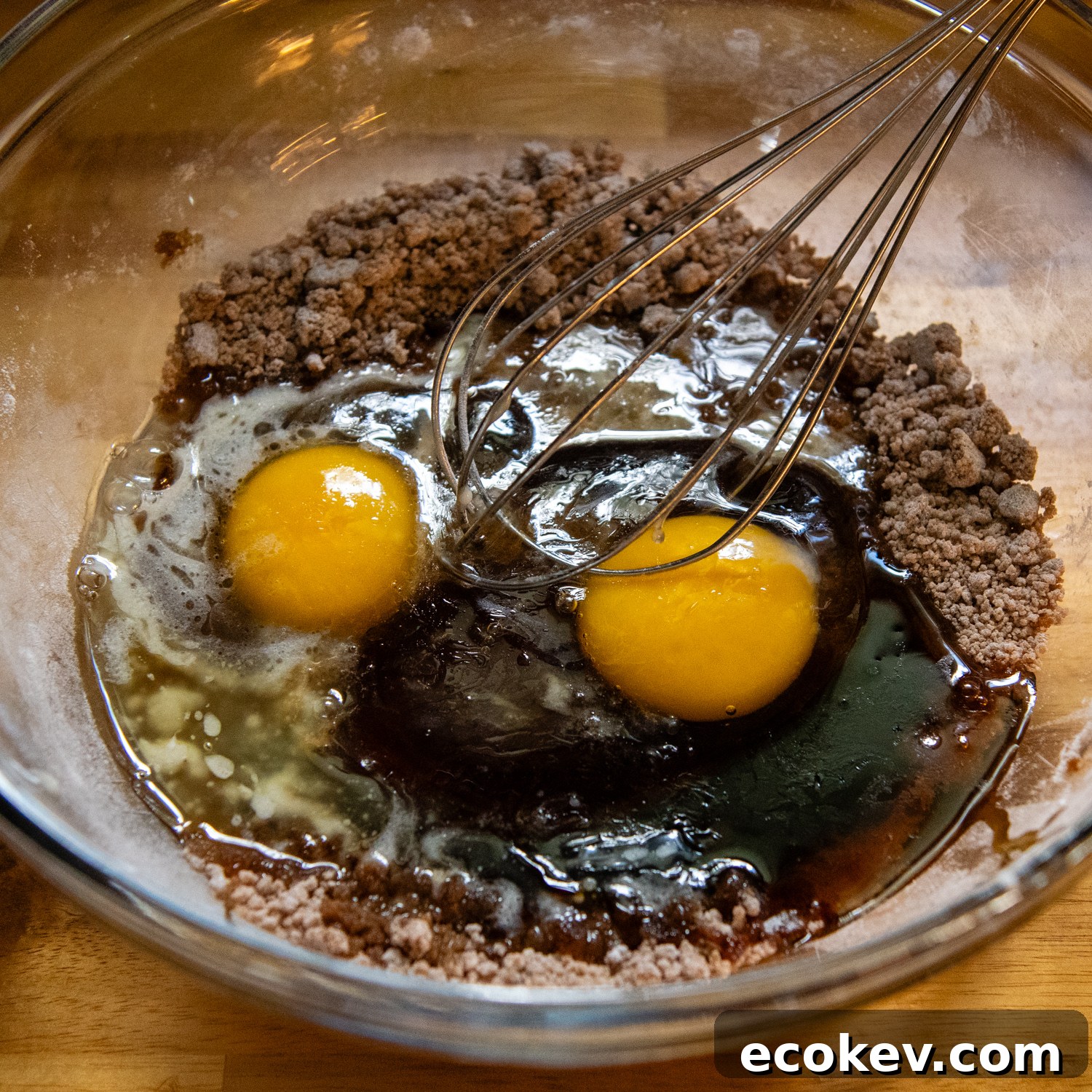 Topping ingredients that include eggs being whisked in a glass bowl.