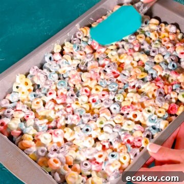 Sticky mixture being spread evenly with a spatula in rectangle pan. 