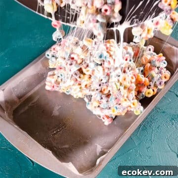 Sticky cereal mixture being added to a greased pan. 