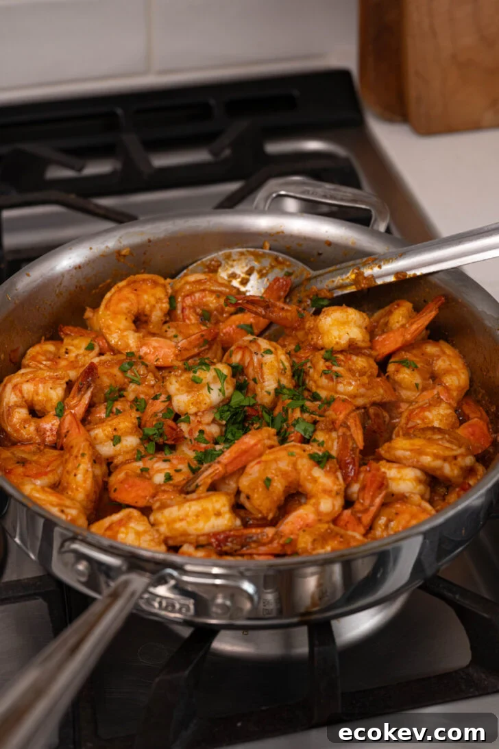 A pan with garlic butter shrimp and parsley.