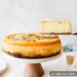A slice of Baileys cheesecake being lifted from the cake stand. White surface and light grey background.