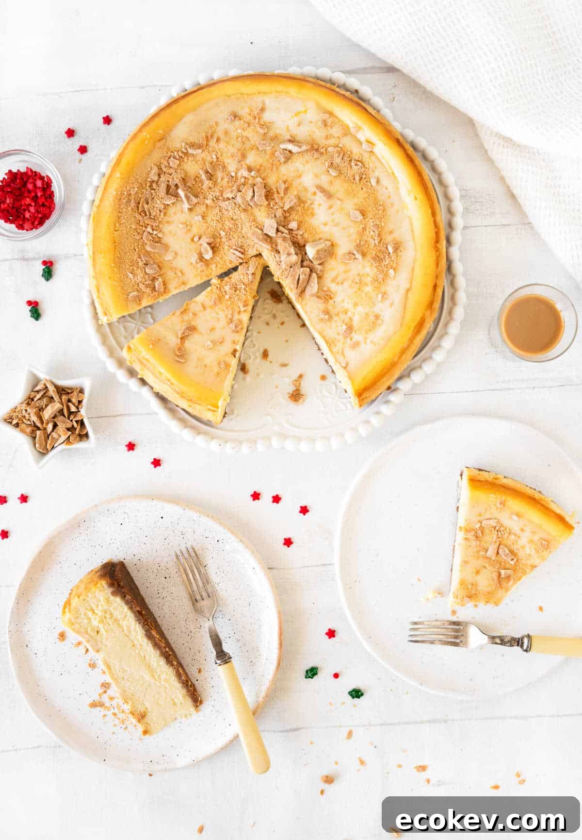 Top view of Baileys cheesecake on a platter. Slices on white plates. White surface. Red, green and gold confetti around. 
