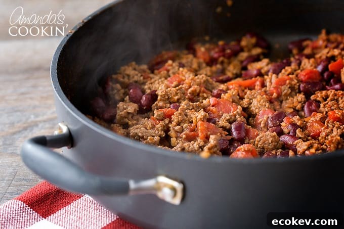 Brown ground beef in a skillet. Drain off fat from ground beef and return beef to pan. Add seasoning mixture, water, beans and tomatoes and stir to combine.