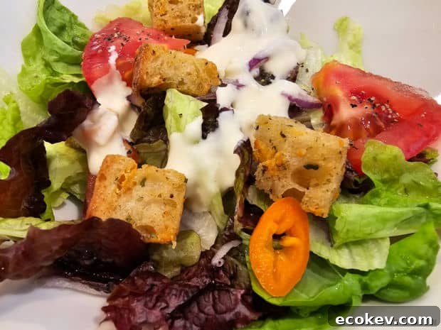 Several air fryer salad croutons are added to a mixed green salad.