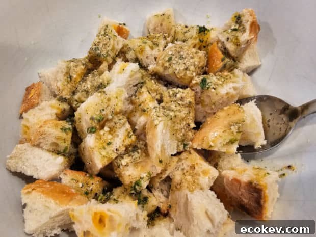 The seasoning mix is poured over bread cubes and tossed well to combine.