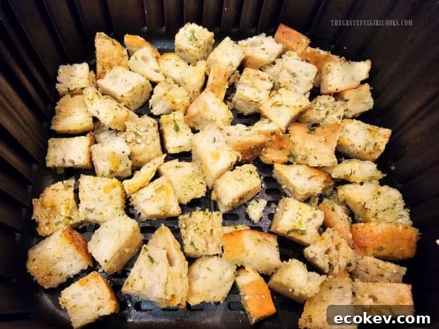 Air fryer basket with seasoned croutons, ready to cook.