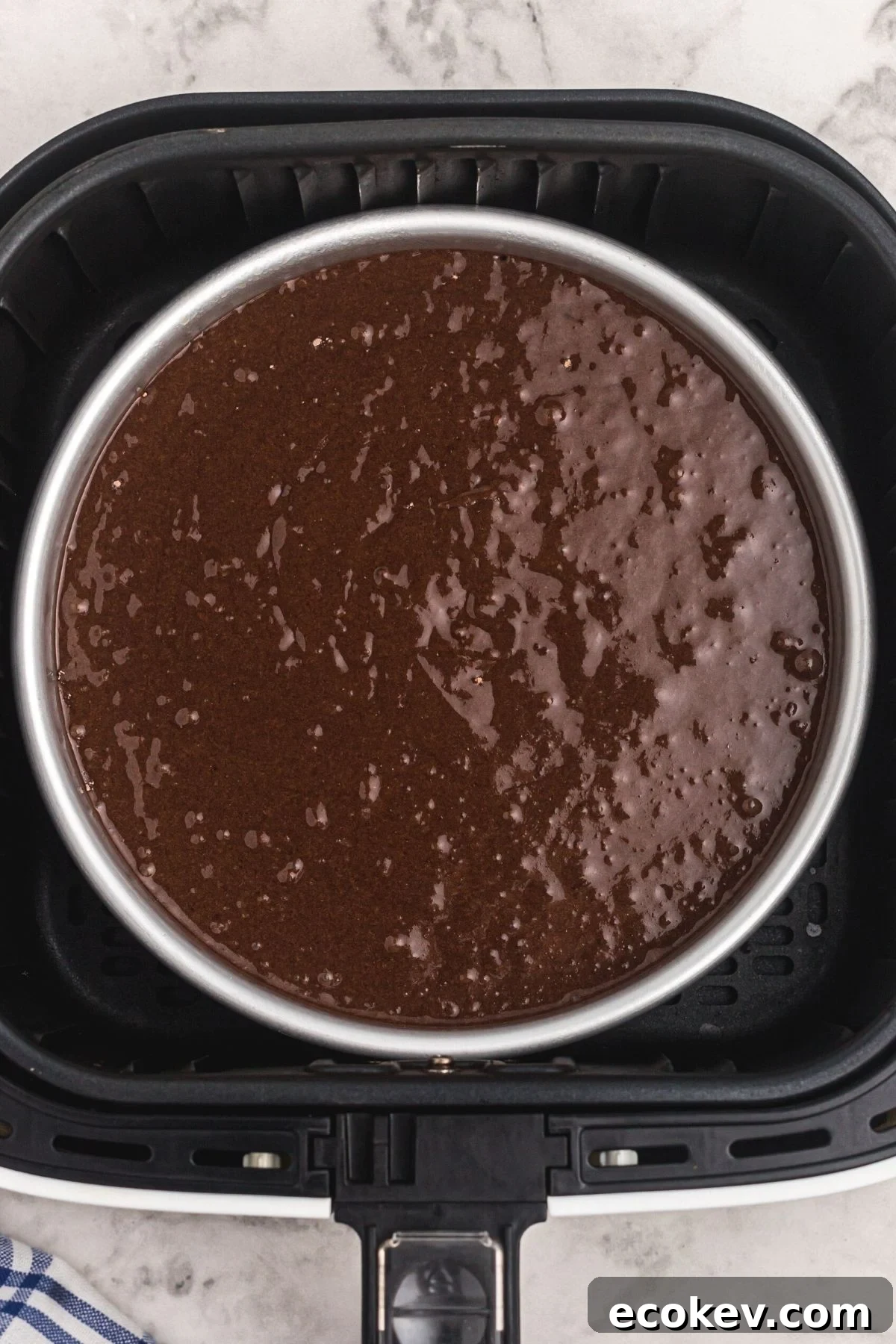 Uncooked cake mix in pan, in an air fryer basket.
