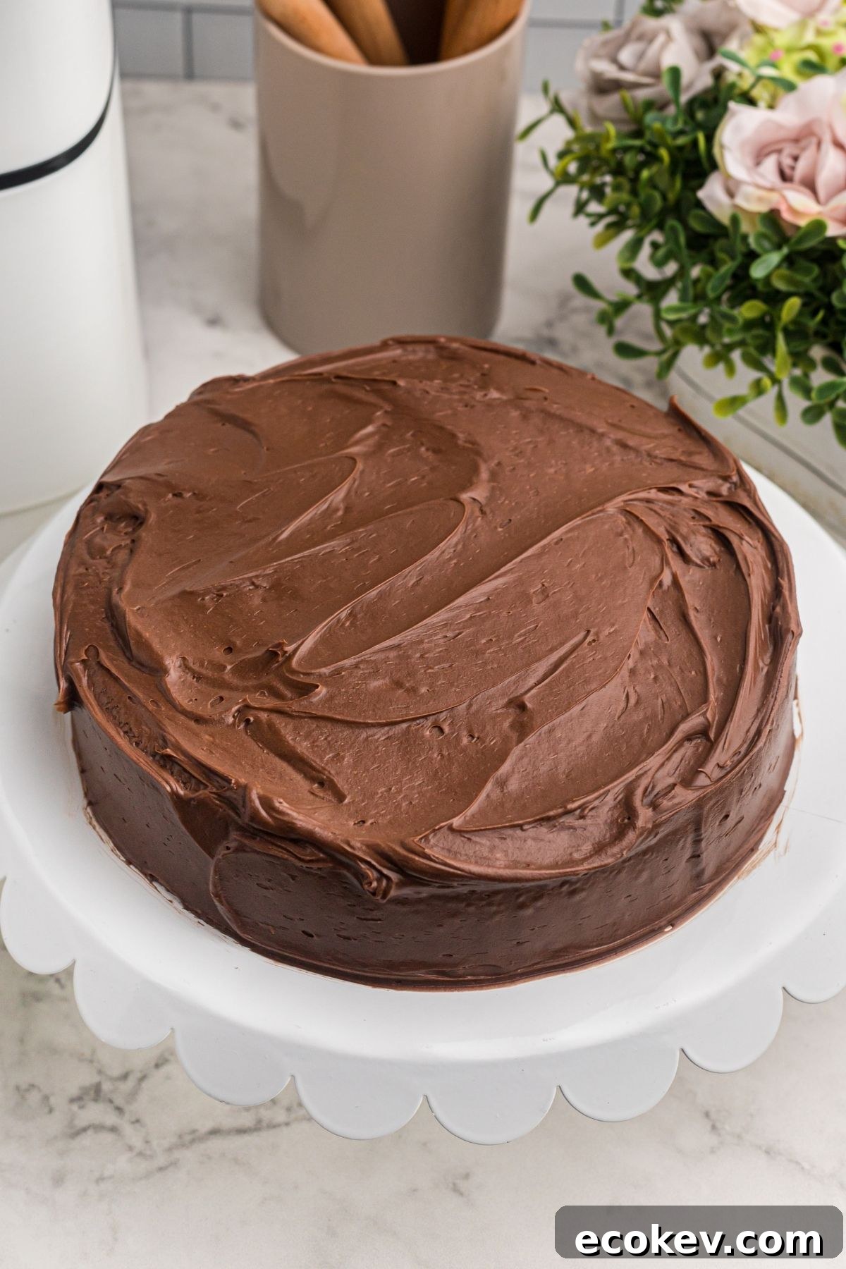 Frosted chocolate cake with chocolate frosting on a white cake platter