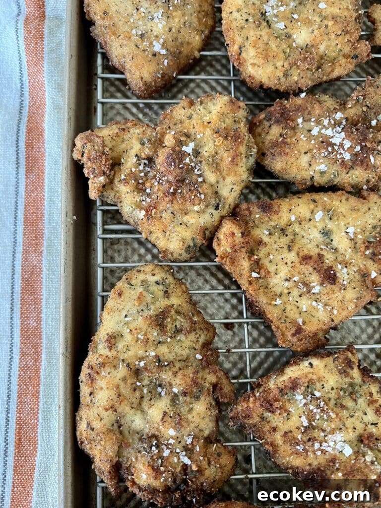 Chicken Cutlets on rack over baking sheet, sprinkled with sea salt flakes.